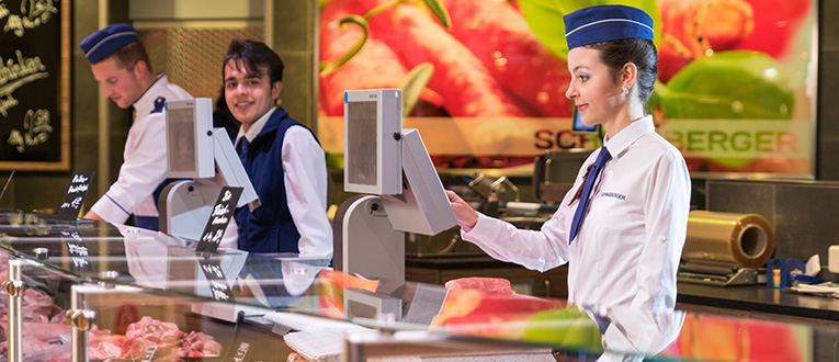 Drei Mitarbeiter in der Feinkostabteilung eines Supermarktes